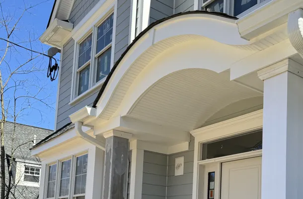 White scrolled entry portico with a fluted column and beadboard soffit by North Valley Exteriors