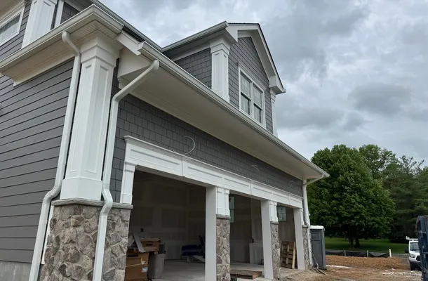 Clean white gutters and downspouts on a gray shake home by North Valley Exteriors